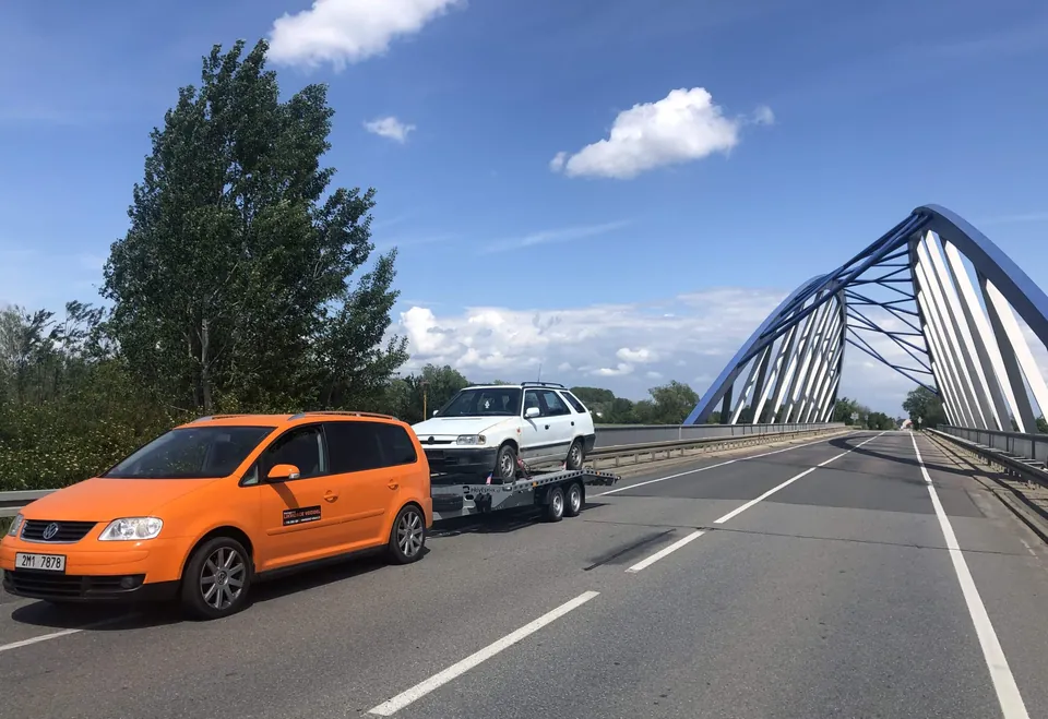 Oranžový VW Touran s přívěsem a naloženým vozem na mostě